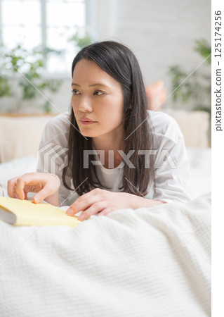 Beautiful woman reading in bed | Study | Hobby | Healthy living image | Well-being girl | Well-being 125174256