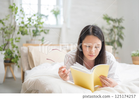 Beautiful woman reading in bed | Study | Hobby | Healthy living image | Well-being girl | Well-being 125174257