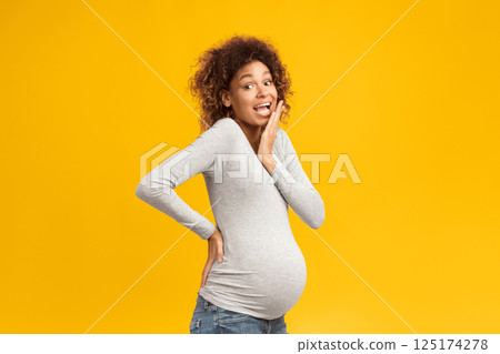 Pregnancy concept. Surprised black woman posing over pink studio background 125174278