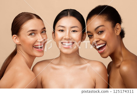 Three Joyful Models Girls Posing Smiling To Camera Standing Shirtless On Gray Background. Studio Shot. Natural Beauty Concept Three Joyful Models Girls Posing Smiling To Camera Standing Shirtless On Gray Background. Studio Shot. Natural Beauty Concept 125174311