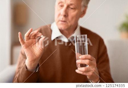 Medication Therapy. Senior Man Holding A Pill And Glass Of Water Sitting On Sofa At Home, Selective Focus 125174335