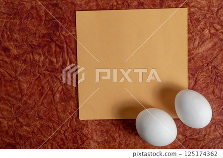 Top view of eggs and blank note on vibrant red fabric background. Top view of eggs and blank note on vibrant red fabric background. 125174362