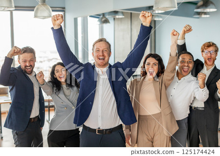 A group of diverse business professionals stand in a modern office, celebrating their success. They are all smiling and laughing, with their arms raised in the air A group of diverse business professionals stand in a modern office, celebrating their success. They are all smiling and laughing, with their arms raised in the air 125174424
