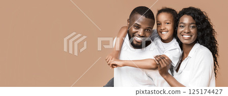 Portrait of positive black family of three, mother, father and their little daughter looking at camera over yellow background, copy space Portrait of positive black family of three, mother, father and their little daughter looking at camera over yellow background, copy space 125174427