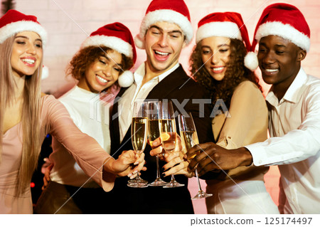 Christmas. Happy Young People Clinking Glasses Drinking Champagne Celebrating Xmas Standing Against Wall Indoor Christmas. Happy Young People Clinking Glasses Drinking Champagne Celebrating Xmas Standing Against Wall Indoor 125174497