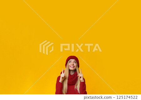 Happy blonde girl in warm clothes showing up with fingers Happy blonde girl in warm clothes showing up with fingers 125174522