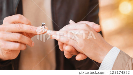 CLose up of man putting engagement ring on female finger outdoors, marriage and engagement concept CLose up of man putting engagement ring on female finger outdoors, marriage and engagement concept 125174852