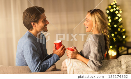Cozy winter holidays. Loving couple drinking hot chocolate on Christmas eve 125174862
