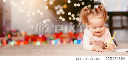 Christmas art. Little girl drawing on floor near xmas tree, empty space 125174864