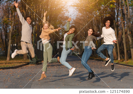 Carefree international students jumping in the air, having fun in park Carefree international students jumping in the air, having fun in park 125174890