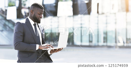 Successful Afro Entrepreneur Working On Laptop During Coffee Break In City. Empty Space 125174939