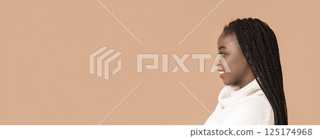 African American woman with long, beautifully braided hair smiles softly while positioned against a warm, neutral background, copy space African American woman with long, beautifully braided hair smiles softly while positioned against a warm, neutral background, copy space 125174968