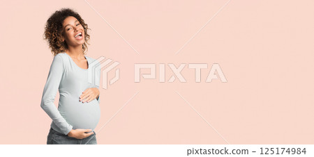 Excited african-american pregnant woman touching belly and laughing on white background Excited african-american pregnant woman touching belly and laughing on white background 125174984