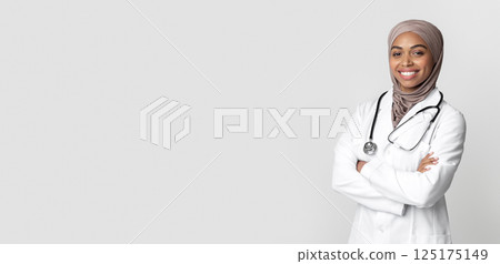 Medical Career For Muslim Women. Portrait Of Black Islamic Women Doctor Standing With Folded Arms And Looking At Camera, Light Background Medical Career For Muslim Women. Portrait Of Black Islamic Women Doctor Standing With Folded Arms And Looking At Camera, Light Background 125175149
