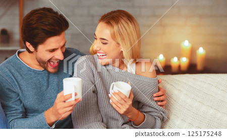 Evening At Home. Loving Spouses Laughing And Drinking Coffee Sitting On Sofa. Selective Focus 125175248