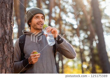 Young hiker with backpack drinking water, having break in forest, empty space Young hiker with backpack drinking water, having break in forest, empty space 125175389