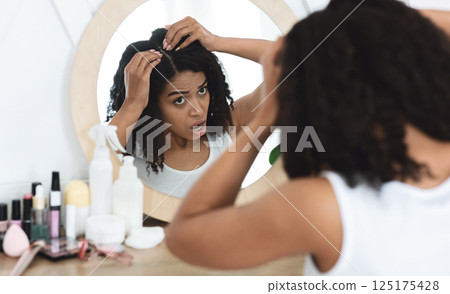 Dandruff Problem. Sad Black Woman Looking At Her Hair Roots With Flaky Scalp In Mirror, Sitting At Dressing Table, Over Shoulder View 125175428