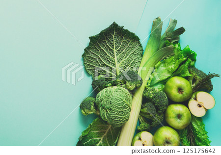 Green vegetables and fruits. Diet, detox and healthy food concept - top view flat lay of vegetarian meals on bright blue background. Ingredients for salad Green vegetables and fruits. Diet, detox and healthy food concept - top view flat lay of vegetarian meals on bright blue background. Ingredients for salad 125175642