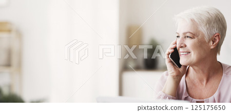 Close up of mature attractive business woman talking by phone with partners or family, looking aside, panorama with free space 125175650