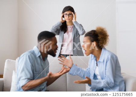 Marriage crisis. Shocked counselor witnessing black spouses fighting during couples psychotherapy. Empty space, selective focus 125175665
