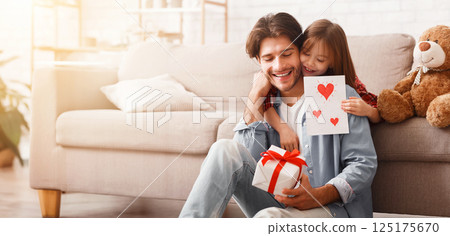 Happy Father Day, sweet girl surprising her daddy with gift and self-made card, happy dad holding gift box, copy space 125175670