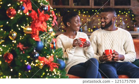 Romantic african american couple drinking coffee on Christmas eve, celebrating winter holidays together. 125175709