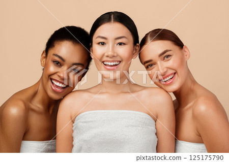 Body Care. Three Joyful Young Women Laughing Looking At Camera Posing Wrapped In White Bath Towels Standing On Gray Background 125175790