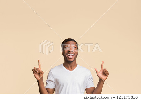 Look Up. African American Millennial Guy Pointing Fingers Upward In Excitement Standing Over Yellow Studio Background. Empty Spacce For Text 125175816