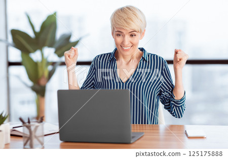 Business Success. Happy Businesswoman Shaking Fists Rejoicing Victory Sitting At Laptop At Work In Modern Office. Selective Focus Business Success. Happy Businesswoman Shaking Fists Rejoicing Victory Sitting At Laptop At Work In Modern Office. Selective Focus 125175888