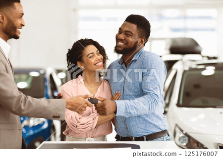 Car Sales. Manager Giving New Auto Key To Family Couple Buying New Vehicle Standing In Dealership Shop. Selective Focus Car Sales. Manager Giving New Auto Key To Family Couple Buying New Vehicle Standing In Dealership Shop. Selective Focus 125176007