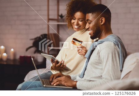 E-Commerce concept. African-american couple using laptop and credit card, buying things online E-Commerce concept. African-american couple using laptop and credit card, buying things online 125176026