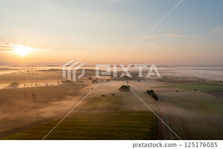 Aerial drone view of rolling landscapes at golden hour with agricultural fields enlightened by sunrise Aerial drone view of rolling landscapes at golden hour with agricultural fields enlightened by sunrise 125176085