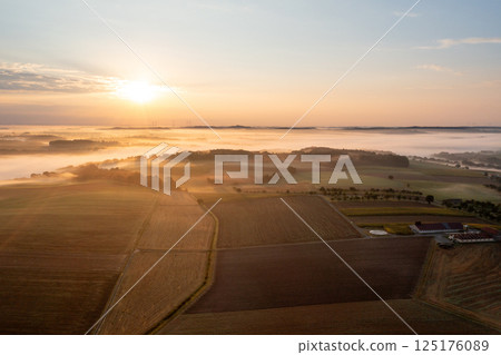 Aerial view with rural scenery at sunrise with foggy agricultural fields Aerial view with rural scenery at sunrise with foggy agricultural fields 125176089