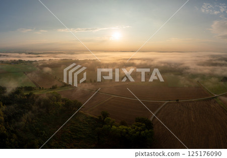 Drone aerial view at golden hour with foggy rolling agricultural fields 125176090