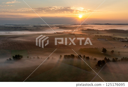 Drone aerial view of agricultural fields covered in fog at golden hour 125176095