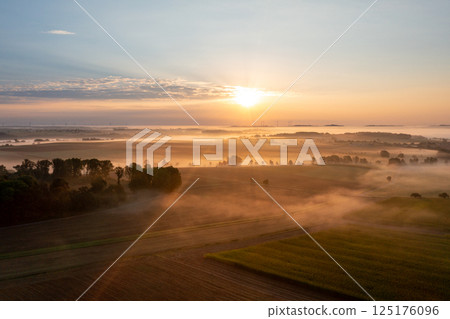 Drone aerial view with foggy agricultural fields at golden hour in the morning Drone aerial view with foggy agricultural fields at golden hour in the morning 125176096