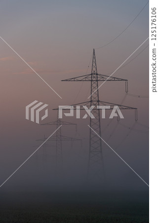 Electrical grid towers in a row on a foggy morning in a german village 125176106