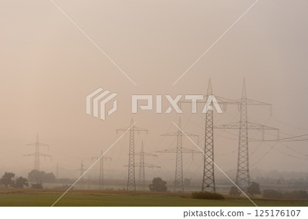 Electricity pylons in a german rural scenery on a foggy morning 125176107