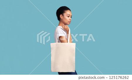 No Plastic. Black Girl Holding Blank White Eco Bag Posing Over Turquoise Studio Background. Panorama, Empty Space No Plastic. Black Girl Holding Blank White Eco Bag Posing Over Turquoise Studio Background. Panorama, Empty Space 125176262