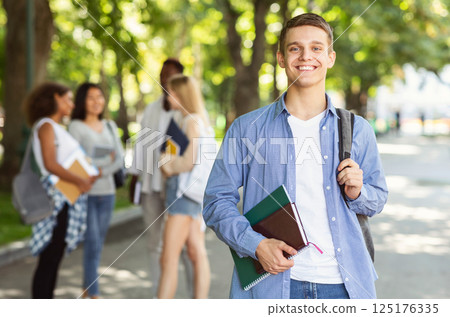 Attractive young guy student spending time with friends together after university, public park 125176335