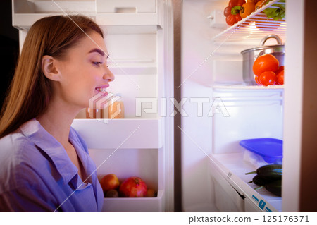 Young woman looking for healthy snack in fridge late in night, free space 125176371