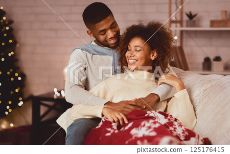 Enjoy winter holidays together. Loving couple relaxing on sofa, man embracing wife 125176415