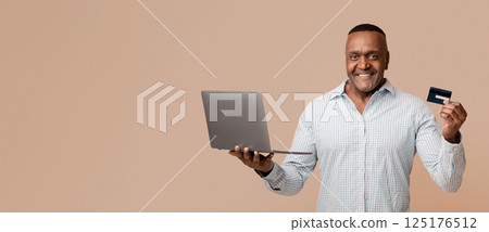 Happy mature afro man holding credit card, paying online by laptop, orange studio background Happy mature afro man holding credit card, paying online by laptop, orange studio background 125176512