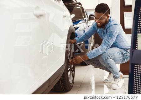 Choosing Car. Afro Guy Checking Wheels Buying Auto In Dealership Store. Copy Space, Selective Focus Choosing Car. Afro Guy Checking Wheels Buying Auto In Dealership Store. Copy Space, Selective Focus 125176577