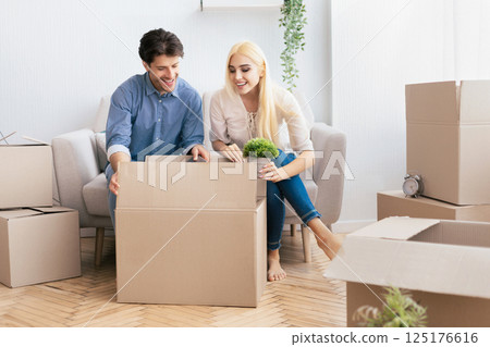 Moving Flat. Husband And Wife Packing Boxes Together Sitting On Couch Indoor. Empty Space Moving Flat. Husband And Wife Packing Boxes Together Sitting On Couch Indoor. Empty Space 125176616
