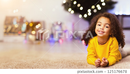 Cute friendly afro little girl resting near awesome Christmas offer, empty space 125176678