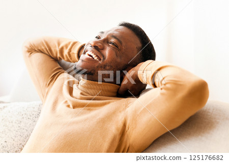Enjoying Weekend. Happy Black Guy Relaxing Sitting On Couch Holding Hands Behind Head At Home. 125176682