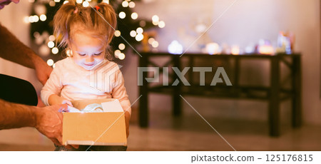 Christmas magic. Amazed little girl opening glowing Xmas gift Christmas magic. Amazed little girl opening glowing Xmas gift 125176815