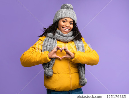 I Love Winter. Cheerful Black Woman Gesturing Heart Shape Smiling To Camera Posing Over Purple Studio Background, Wearing Warm Clothes. Love, Romance, Happy Winter Season Concept I Love Winter. Cheerful Black Woman Gesturing Heart Shape Smiling To Camera Posing Over Purple Studio Background, Wearing Warm Clothes. Love, Romance, Happy Winter Season Concept 125176885
