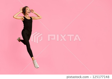 Fitness Lifestyle. Excited Girl In Headphones Jumping Or Running On Yellow Background. Studio Shot, Full Length 125177148